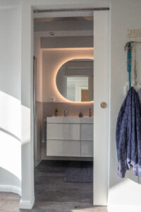 Casa Malina Norderstedt – modernes Badezimmer mit runder Spiegelbeleuchtung im Dachgeschoss